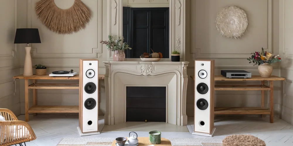 Paire d'enceintes colonne Triangle Borea finition blanche dans un salon, près d'une platine vinyle et d'un ampli