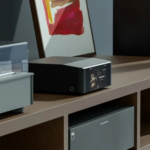 Bluesound NODE ICON posé sur un meuble bas au-dessus d'un amplificateur stéréo NAD