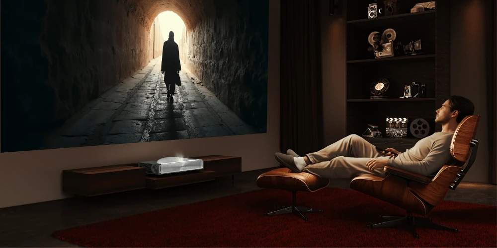 Hisense PX4 Pro posé sur un meuble bas projetant un film sur le mur d’un salon home cinéma, spectateur dans un fauteuil