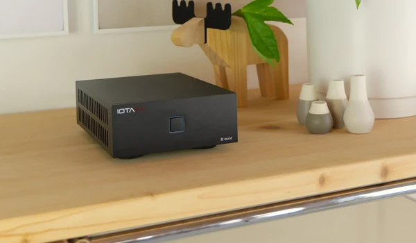 IOTAVX B:ound vu de trois quarts sur un plateau en bois, bouton POWER en façade et logo IOTAVX visible