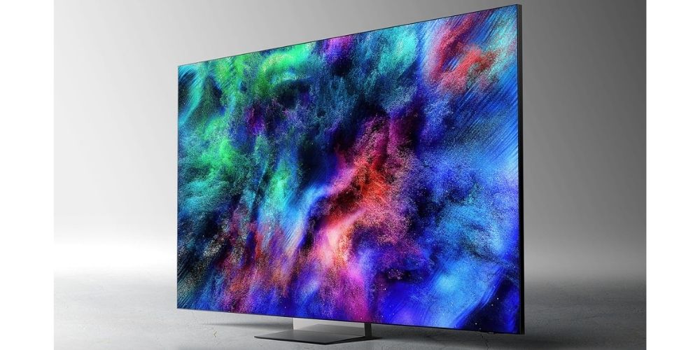 Samsung TMR75R95H vue trois quarts gauche sur fond gris, pied Infinity Air Stand Space Graphite, dalle Micro RGB affichant une image abstraite aux couleurs vives avec profil ultra-fin de 29,6 mm visible