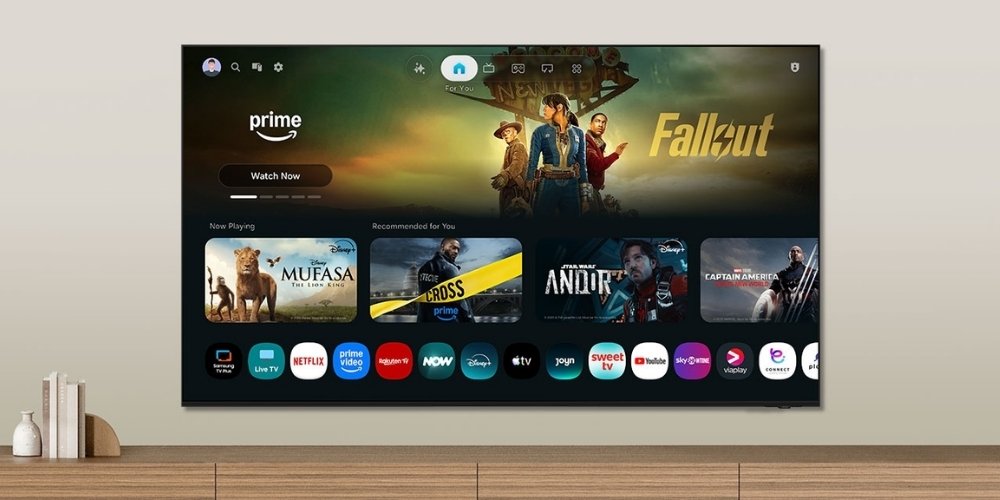 Interface Smart TV Tizen du Samsung TMR75R95H posé sur meuble, écran d'accueil avec applications Netflix, Disney Plus, Prime Video et recommandations personnalisées