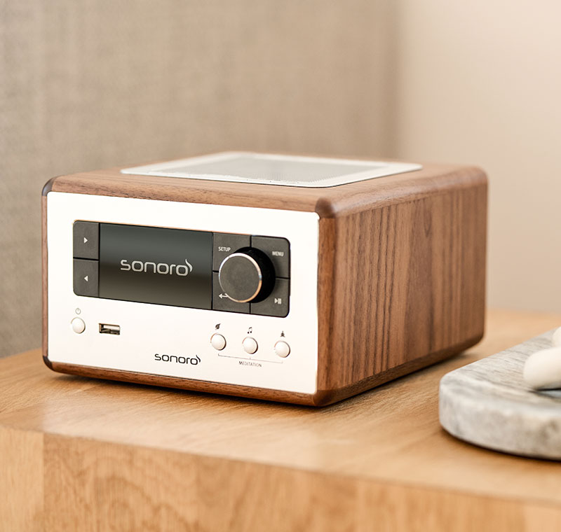 Image 1 | alt : Radio internet sonoro RELAX finition blanc brillant, vue trois quarts face, posée sur une table de chevet en bois dans une chambre