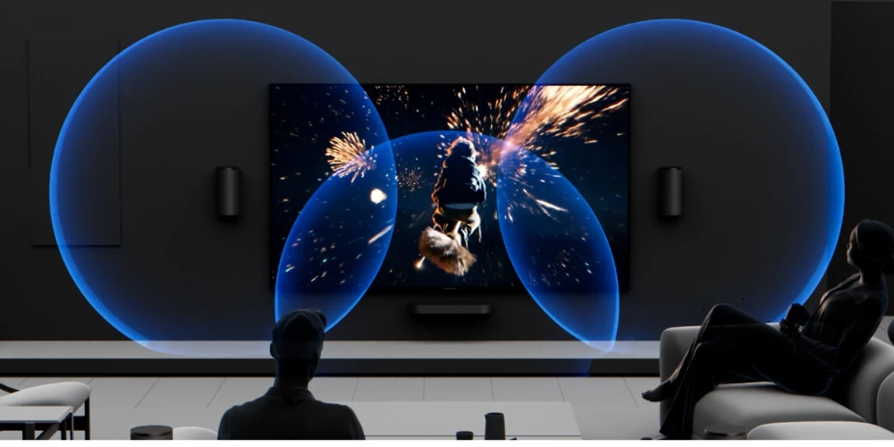Salon sombre avec téléviseur mural affichant un feu d'artifice, halos sonores bleus et enceintes Sony de chaque côté