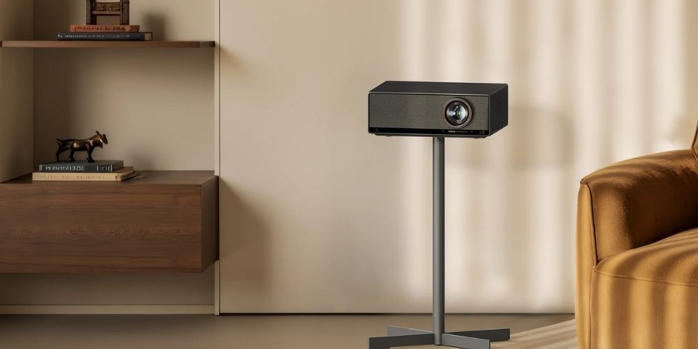 Xgimi Titan sur son pied de sol dédié à base en X métal, positionné en intérieur épuré avec étagère et fauteuil velours doré