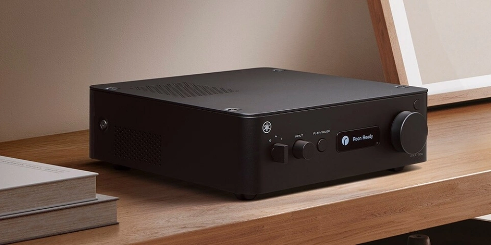 Yamaha WXA-70A en finition noire sur une étagère en bois, écran affichant Roon Ready, entre des livres et un cadre.