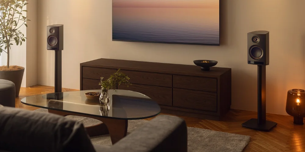 Pieds Yamaha SPS-70A noirs supportant une paire d'enceintes NX-70A sous un televiseur au salon